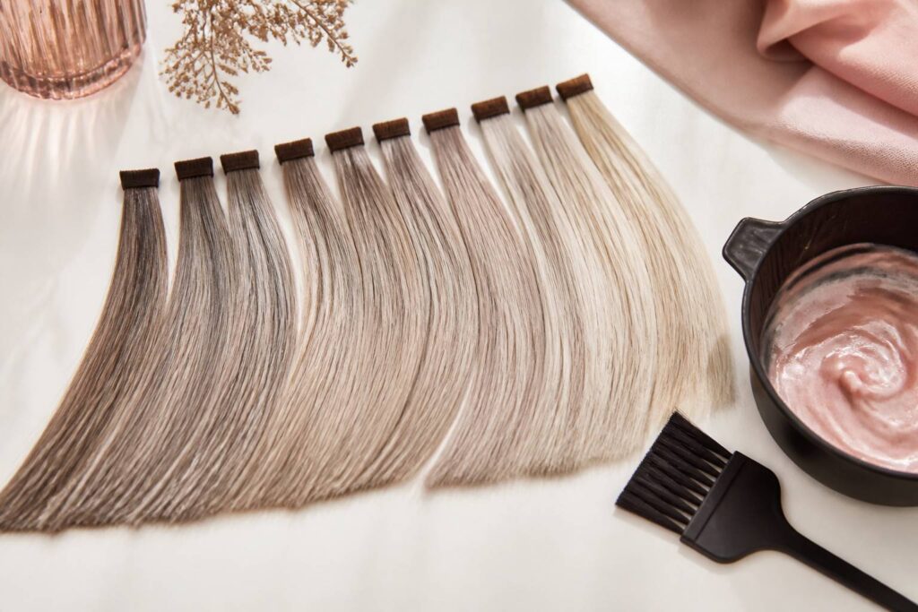 Nuancier de mèches de cheveux blond foncé cendré sur fond clair épuré avec un pinceau de coloration