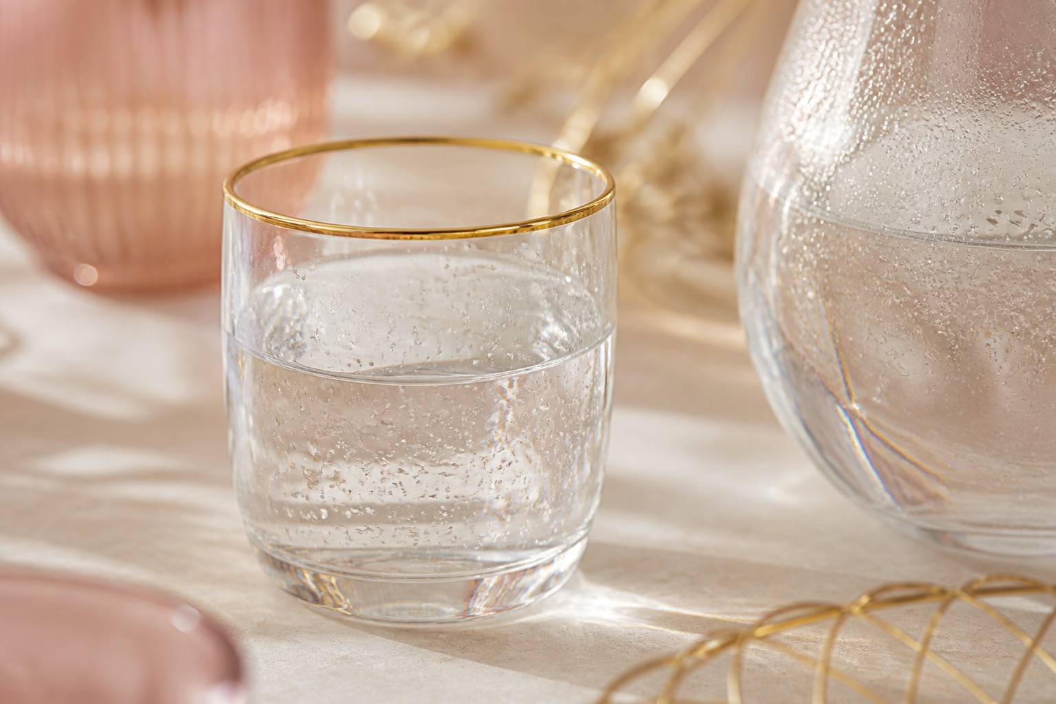 Verre d'eau claire à côté d'une carafe en verre sur table ivoire
